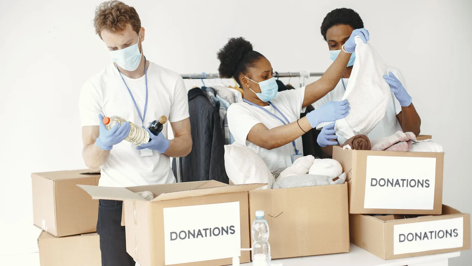 Volunteers in gloves sorting clothes and supplies into donation boxes