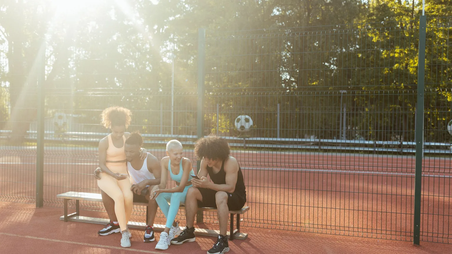Three club members on a bench at the edge of the court after a game, going through options on a phone
