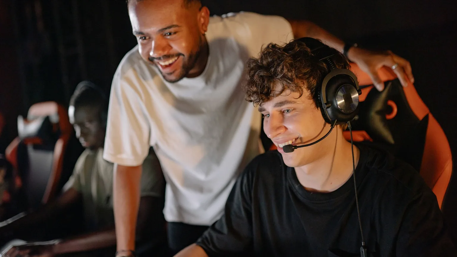 Two gamers in headsets at a LAN session, laughing mid-game