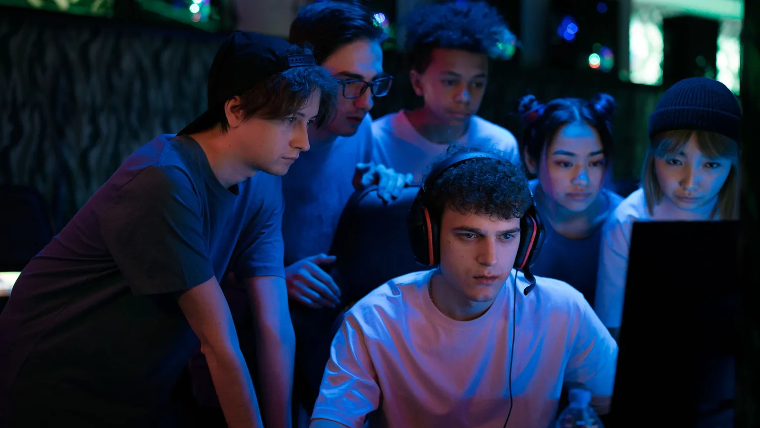 A group of friends crowded round a screen watching a teammate play