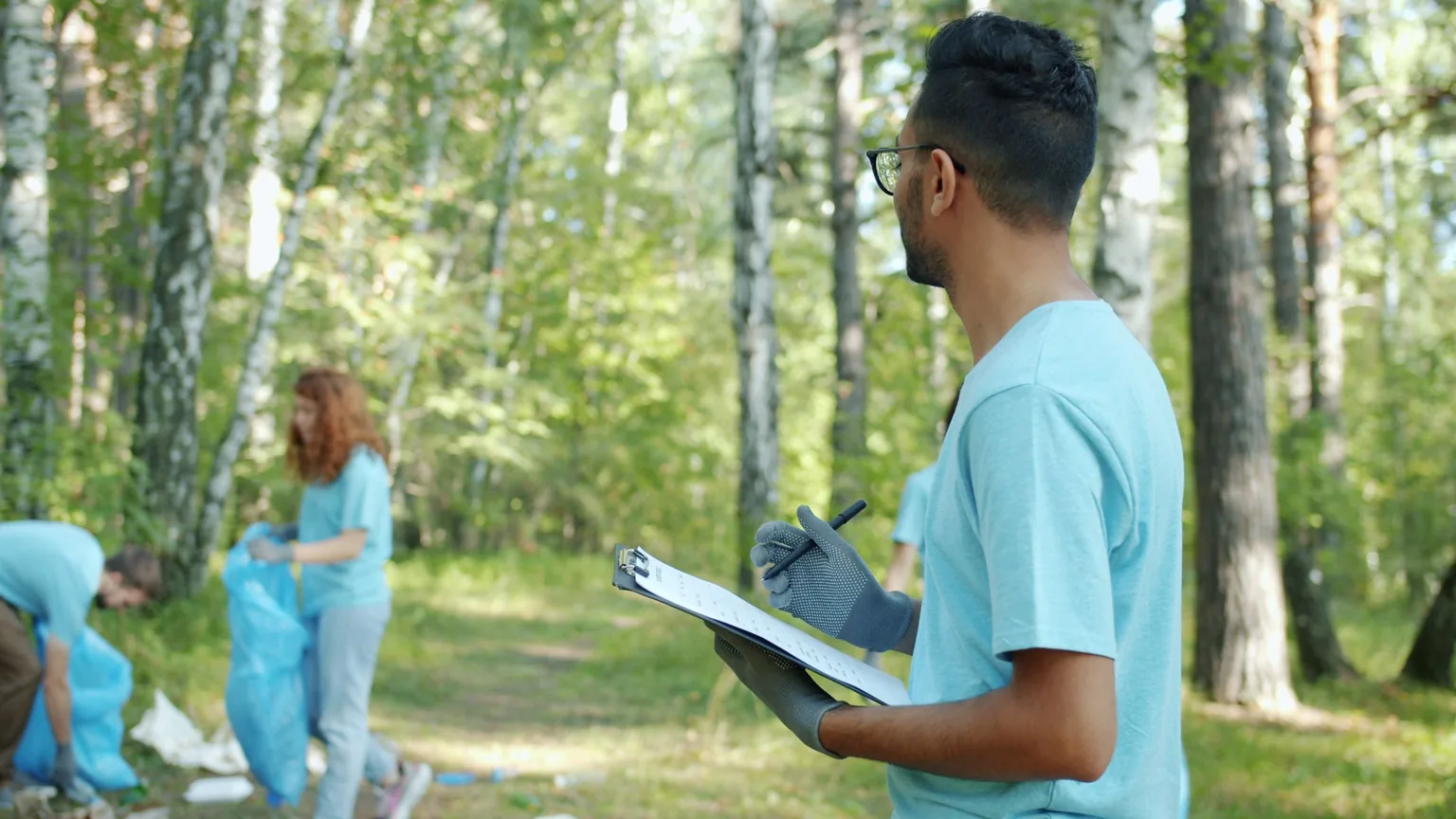 A clean-up volunteer with a clipboard noting what the group has collected in a forest