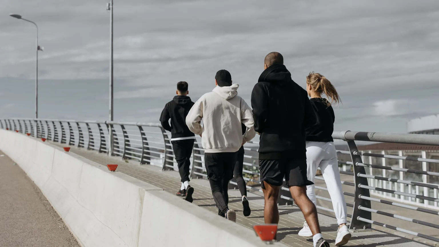 Members of a running club jogging together across a city bridge