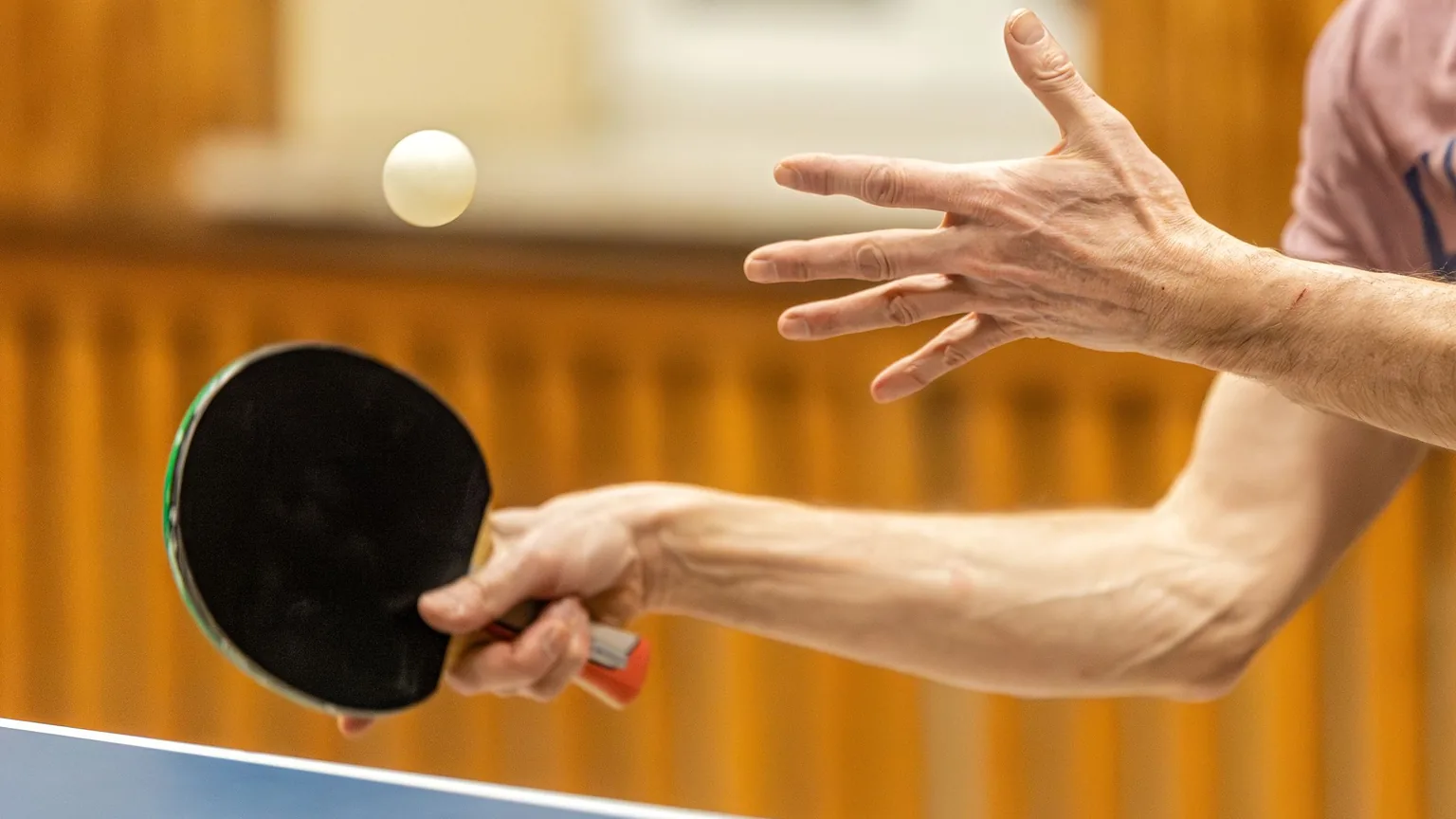 A table tennis player serving, close up