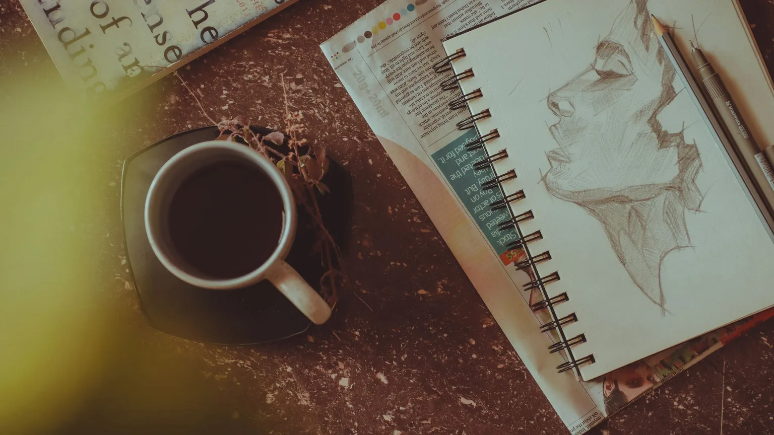 An open sketchbook beside a cup of tea on a cafe table