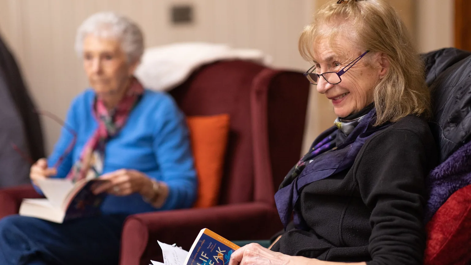 Members of a book club reading and chatting in armchairs