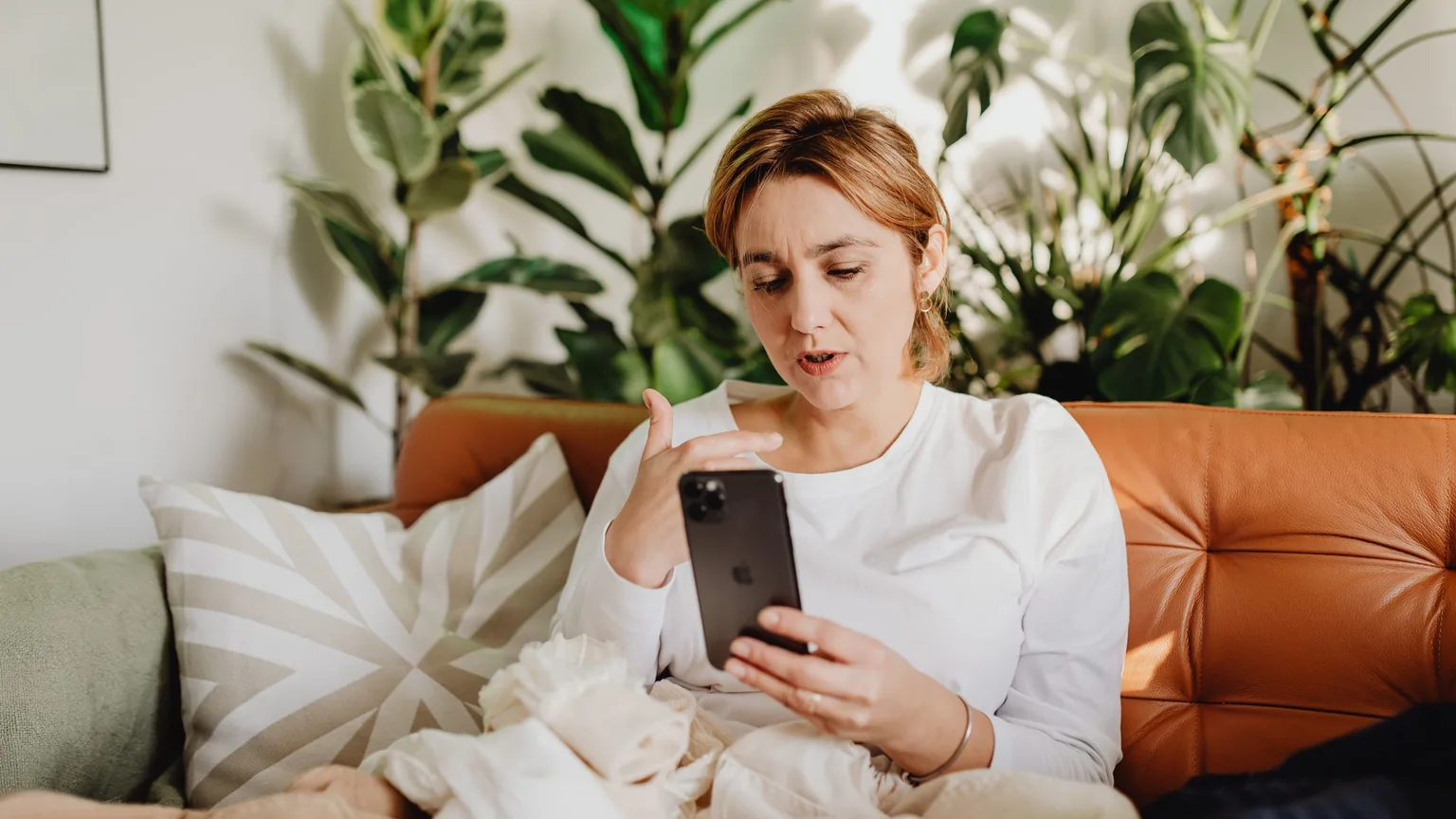 A member at home on the sofa reading a message on her phone