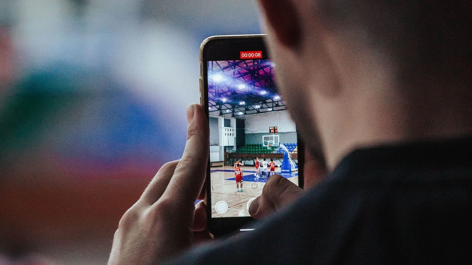 A club member at the side of the court with a phone during the game