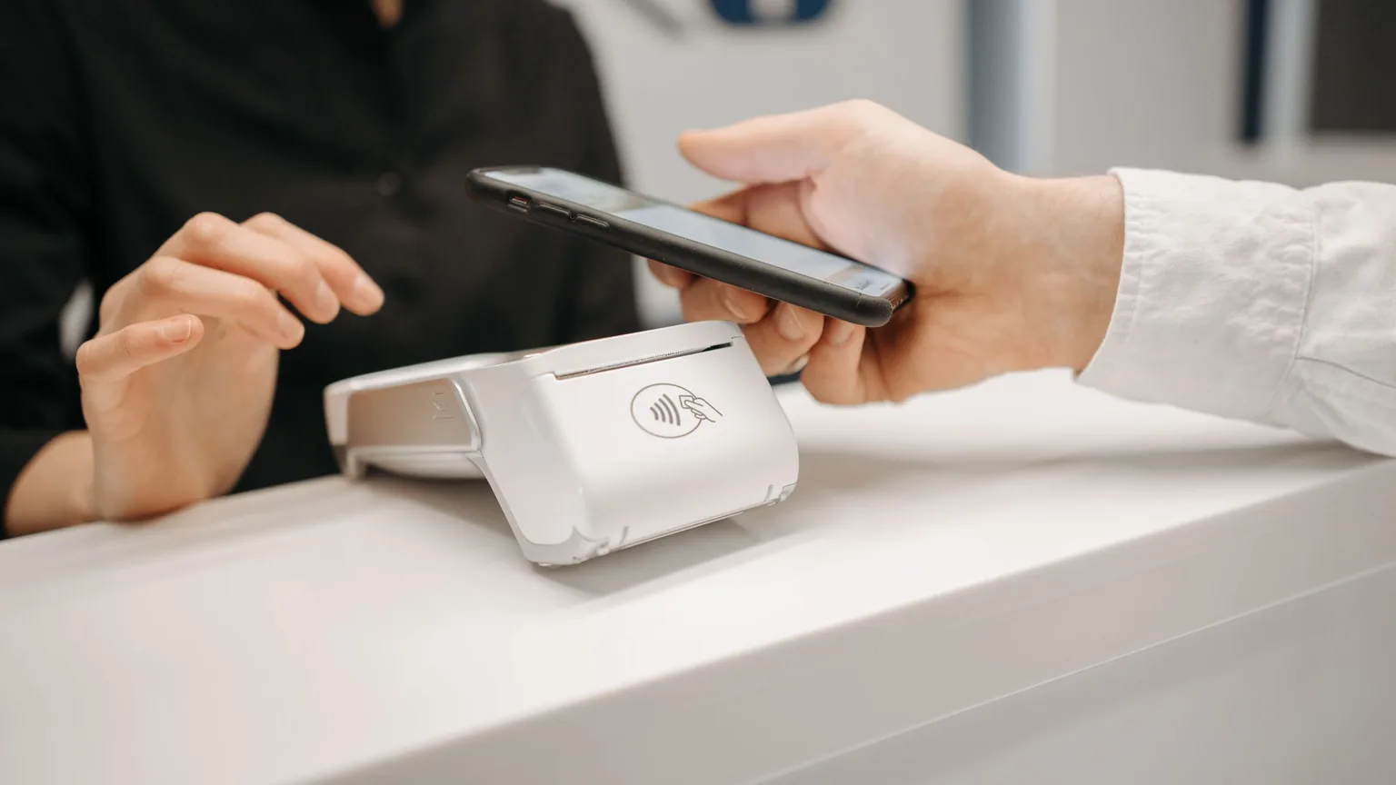 A member tapping a phone on a card reader at the front desk