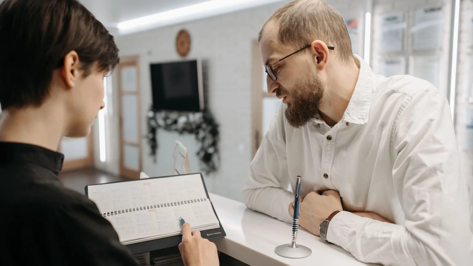 A front-desk manager showing a member the booking diary