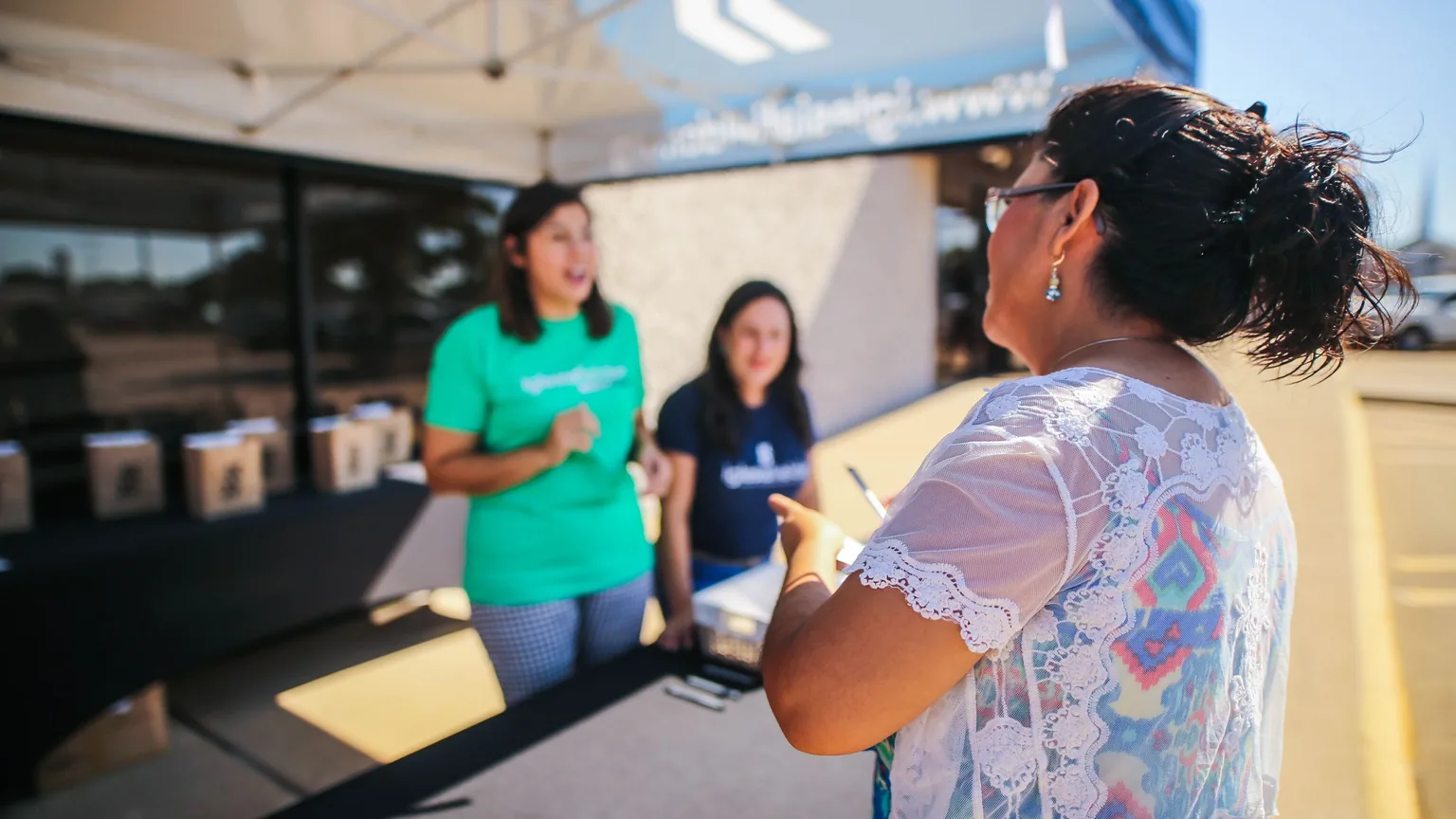Volunteers talking to a visitor at an outdoor welcome booth
