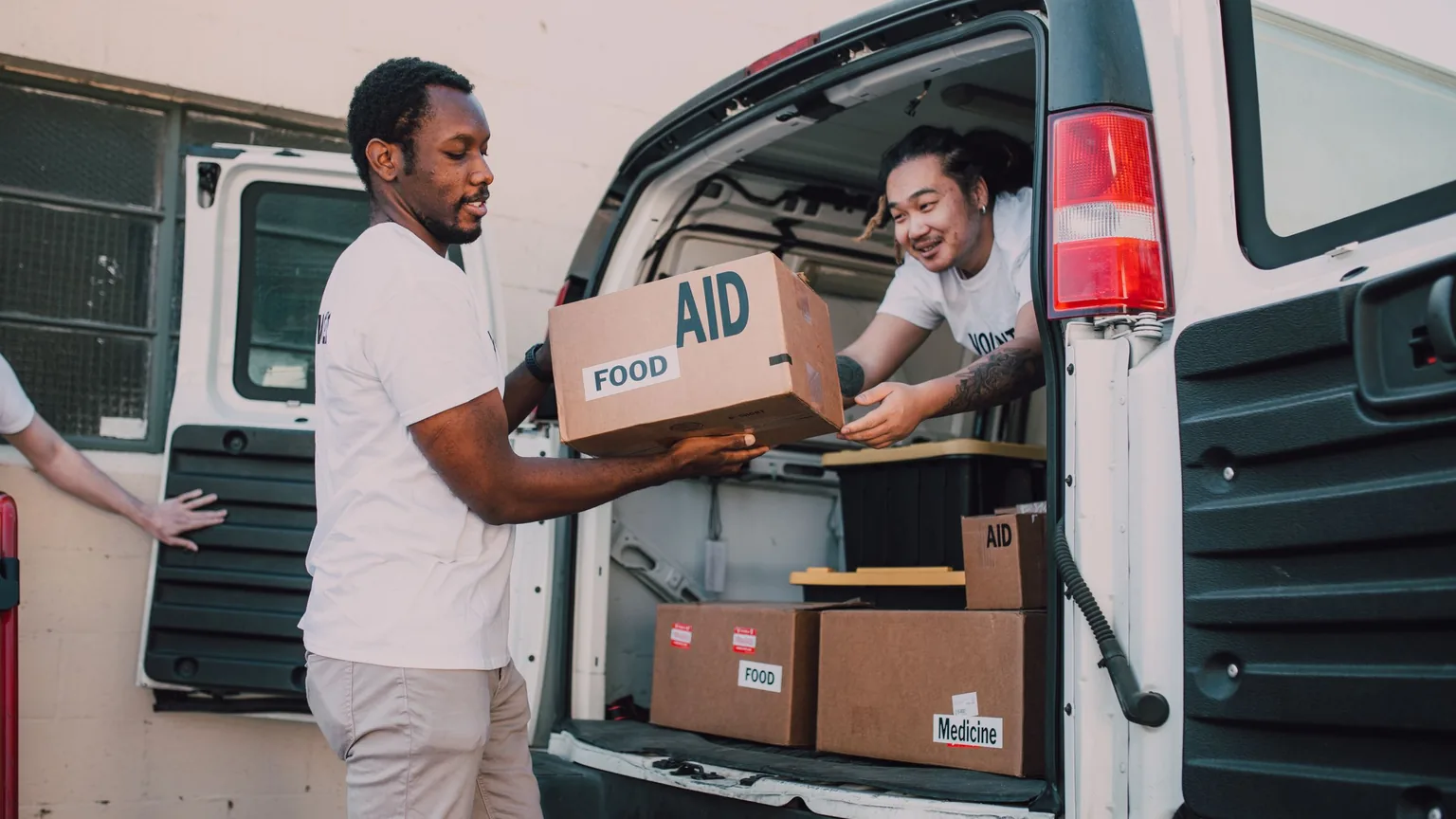 Two volunteers loading boxes of food aid into a van