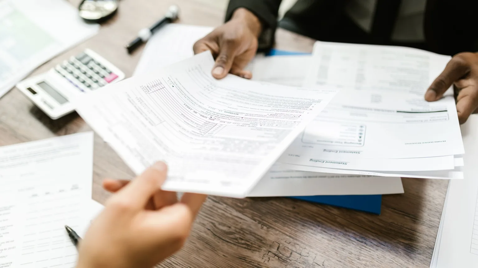 A printed document being handed across a desk to be read