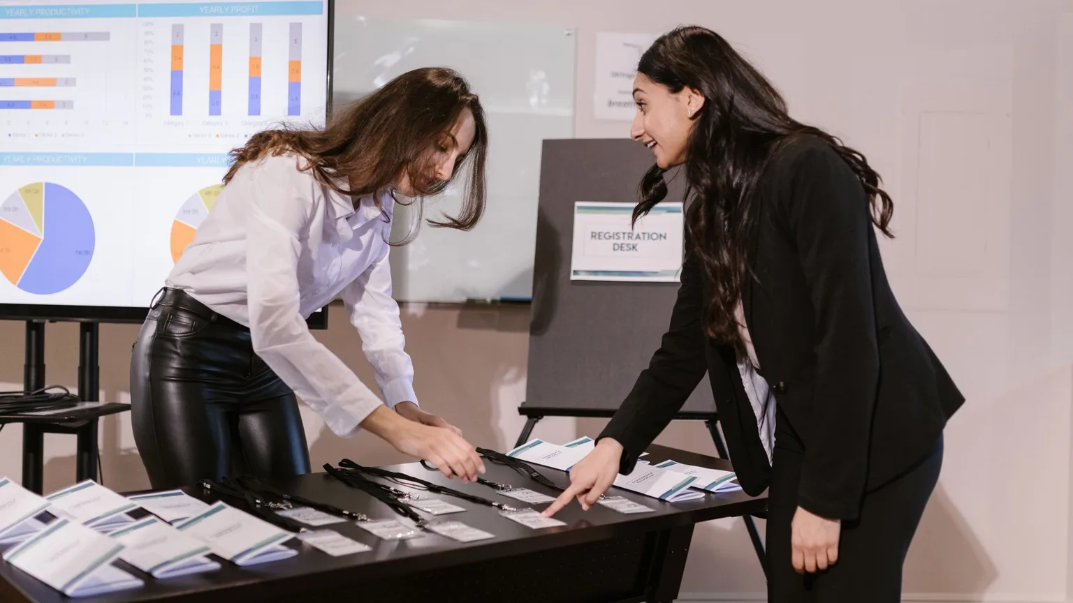 Two organisers laying out name badges and lanyards on a registration desk