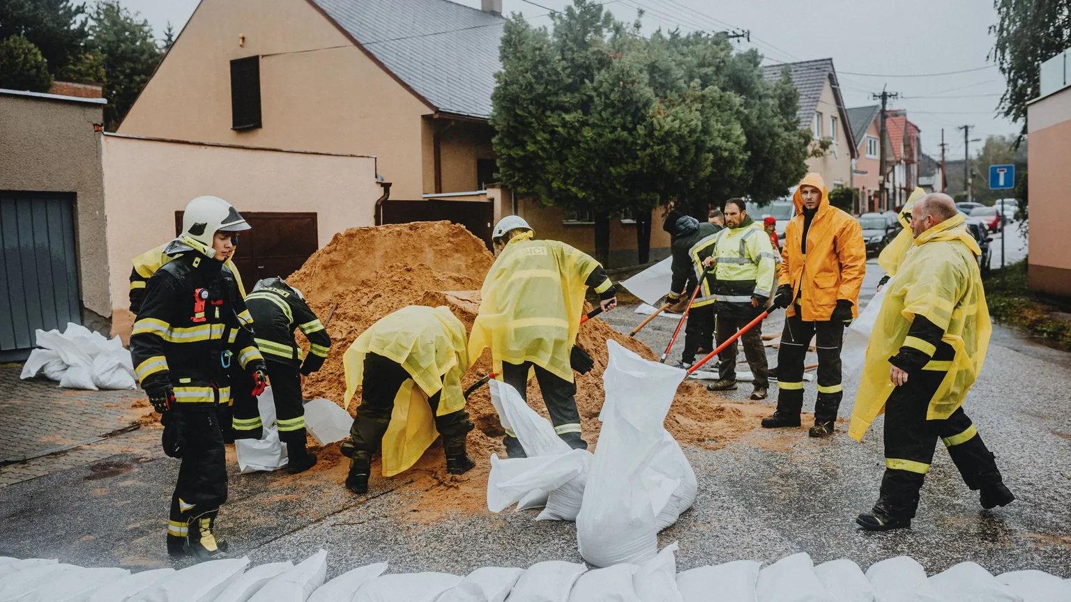 An emergency crew in helmets and reflective gear working on a flooded street