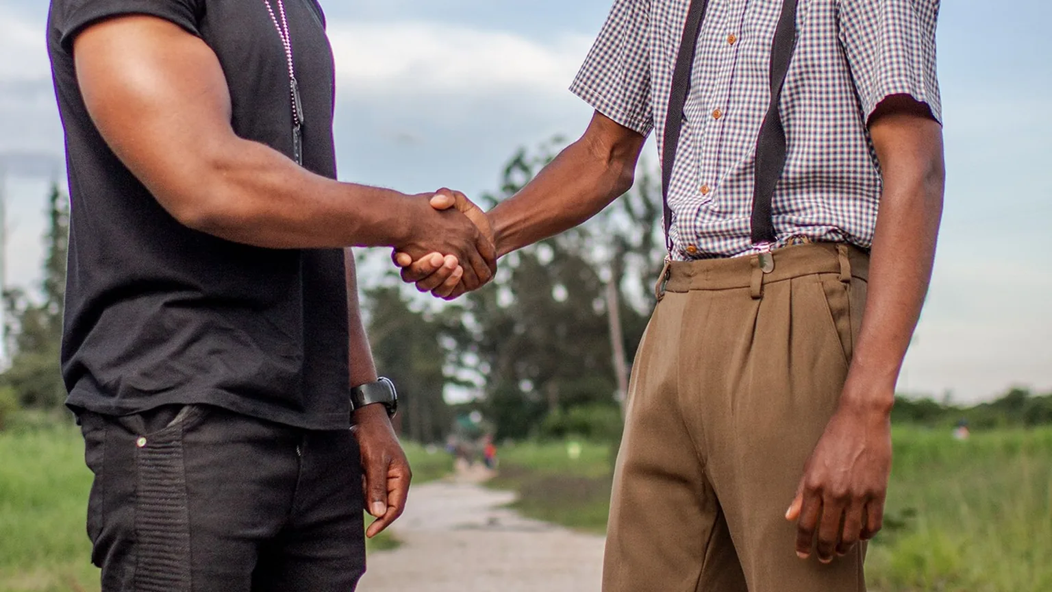 Two men shaking hands in welcome outdoors
