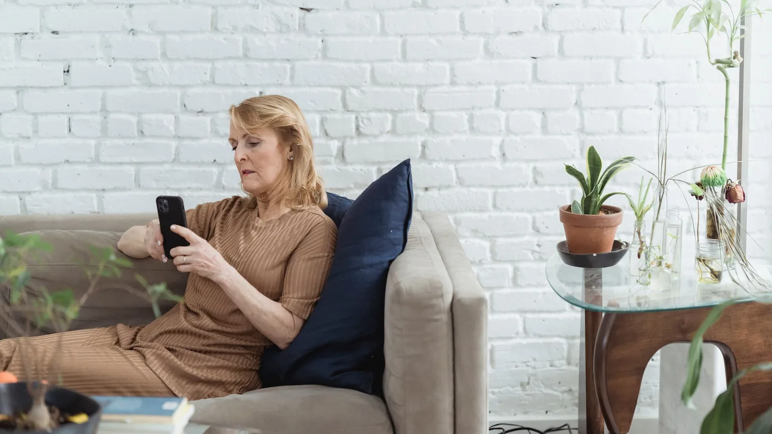 A committee member on the sofa sending a message from her phone