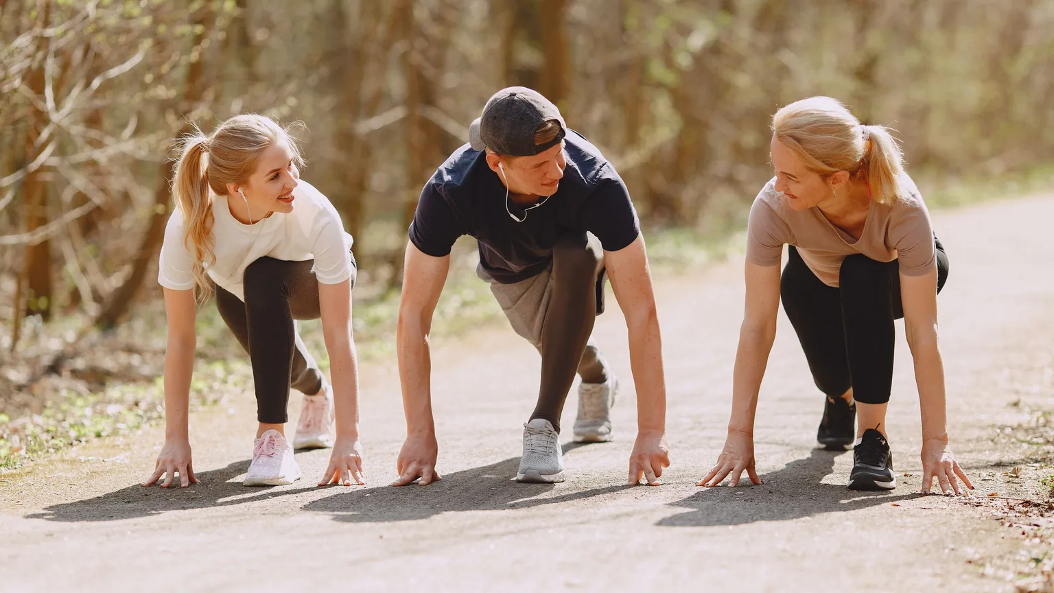 Three members of a running club in the ready position before a morning run