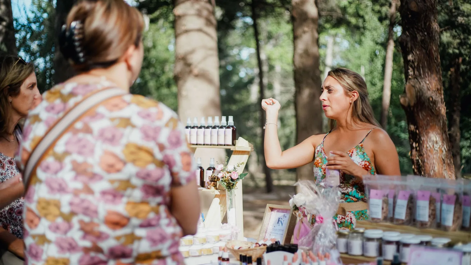 Customers at an outdoor market stall selling handmade cosmetics