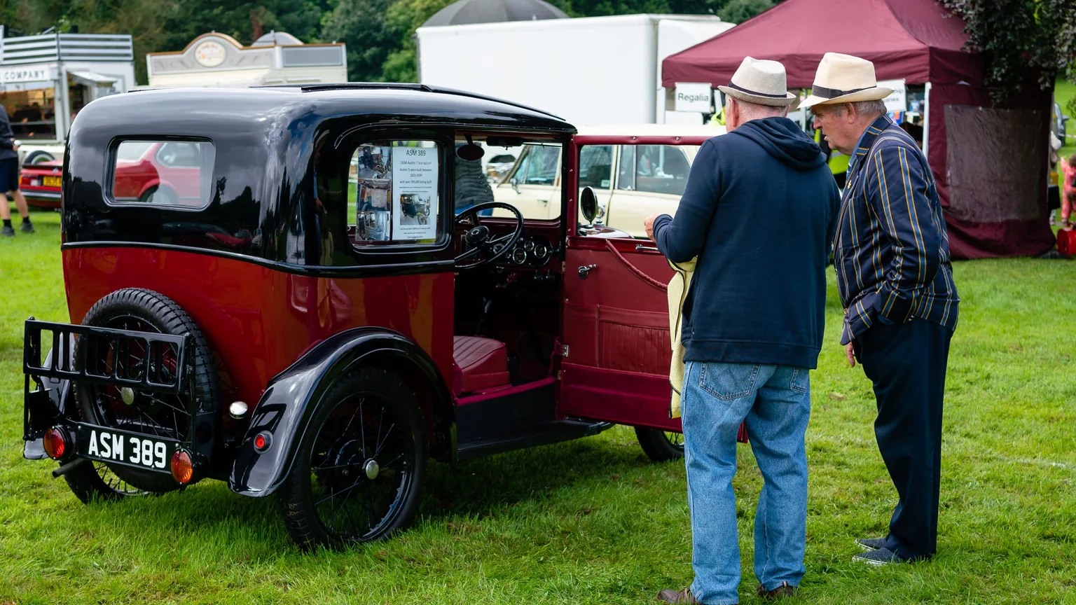 Two classic car owners talking beside a vintage car at a club meet