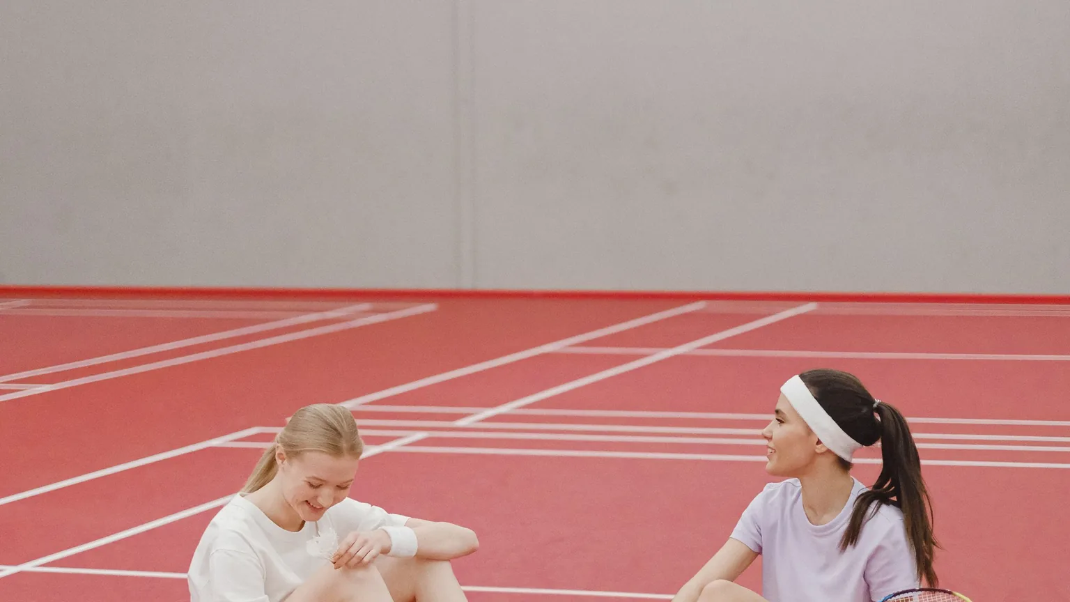 Two players sitting on the badminton court between games