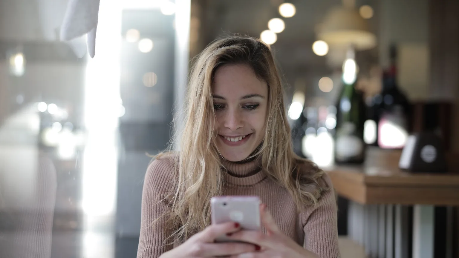 A new member smiling at a welcome message on her phone in a cafe