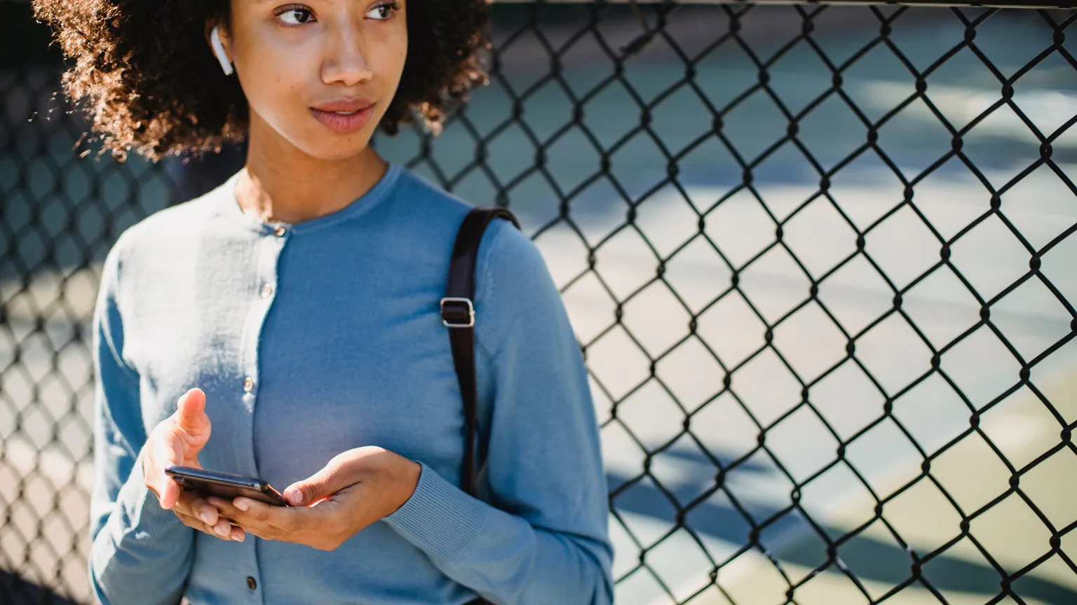 A member checking her phone at the court fence between games