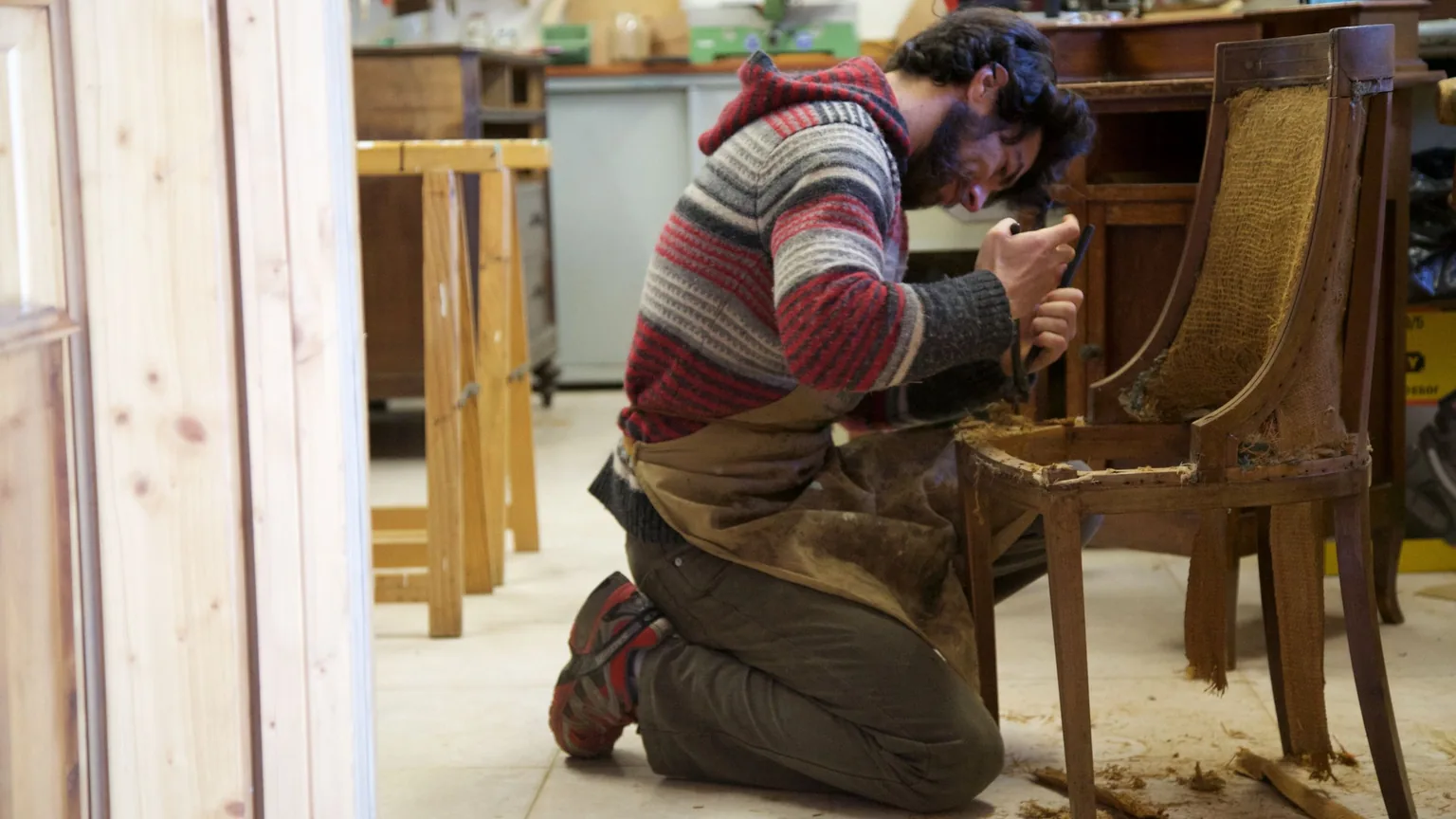 A craftsman restoring a wooden chair by hand in his workshop